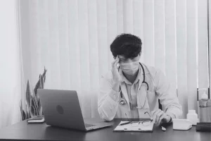 Überlasteter Arzt im Krankenhaus bei administrativer Arbeit – Fachkräftemangel und Organisationsproblem